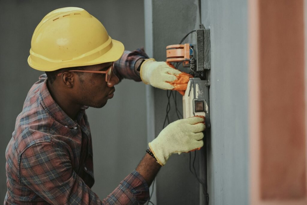 Electrician in a hard hat and gloves testing electrical equipment